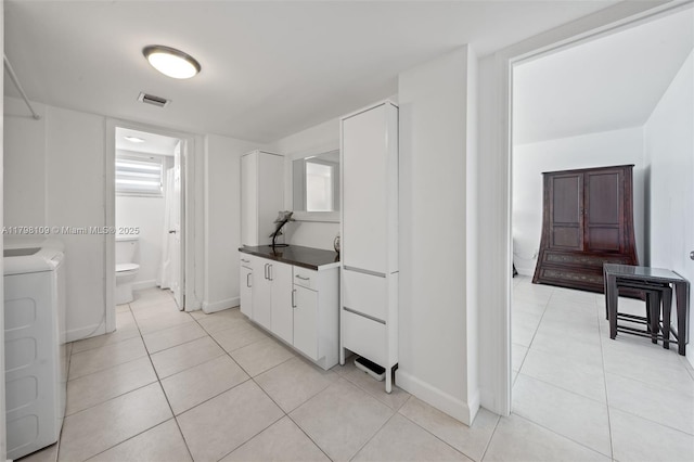 2751 S Ocean Dr Unit 403S, Hollywood, FL 33019 - kitchen featuring light tile patterned floors, washer / dryer, white cabinetry, and dark countertops