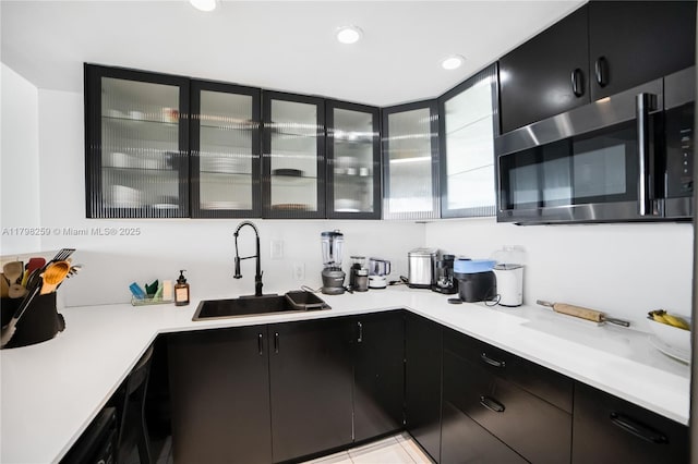 100 NW Bayview Dr Unit 1502, Sunny Isles Beach, FL 33160 - kitchen with dark cabinets, stainless steel microwave, light countertops, glass insert cabinets, and recessed lighting