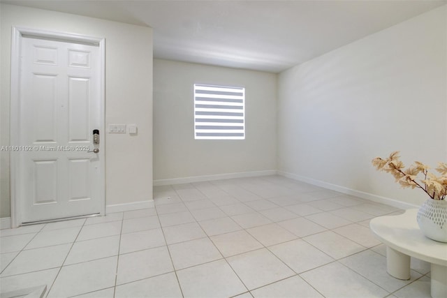 spare room featuring baseboards and light tile patterned flooring