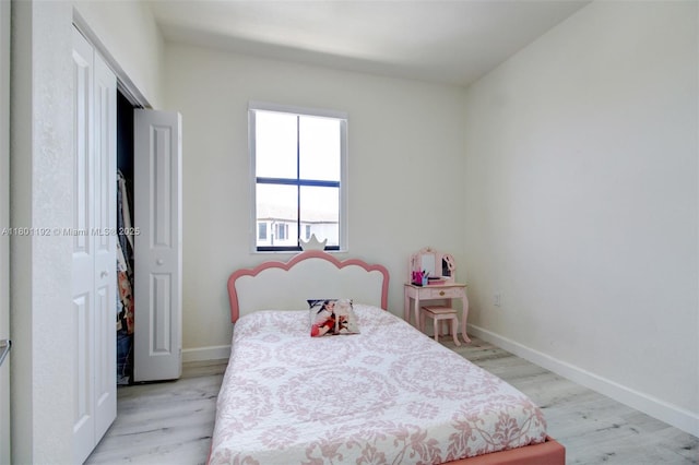 bedroom with light wood-style floors, baseboards, and a closet