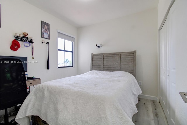 bedroom with wood finished floors, a closet, and baseboards