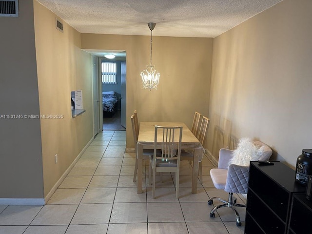 dining area featuring a textured ceiling, light tile patterned flooring, a chandelier, and baseboards