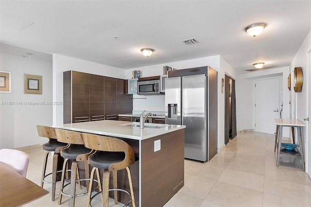 1900 N Bayshore Dr Unit 2915, Miami, FL 33132 - kitchen featuring stainless steel appliances, light countertops, light tile patterned floors, a breakfast bar, and dark brown cabinets