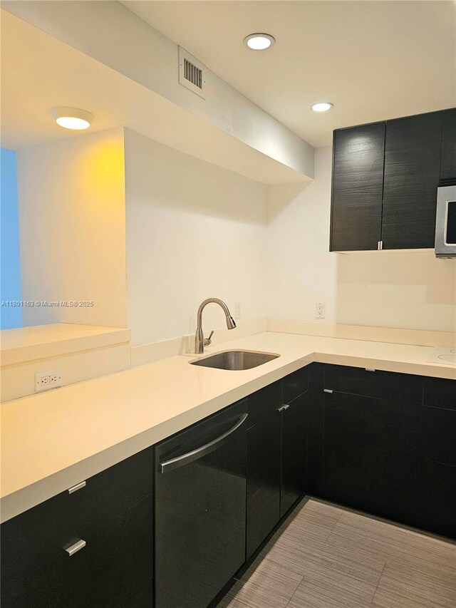 1000 W Ave Unit 715, Miami Beach, FL 33139 - kitchen with dishwashing machine, a sink, dark cabinets, light countertops, and stainless steel microwave
