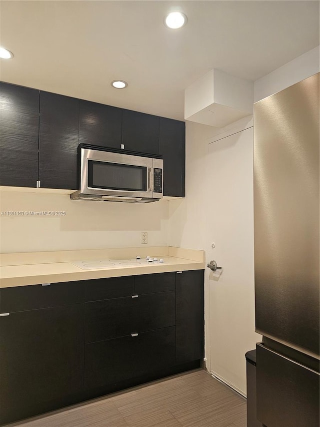 1000 W Ave Unit 715, Miami Beach, FL 33139 - kitchen with dark cabinets, stainless steel microwave, light countertops, recessed lighting, and modern cabinets