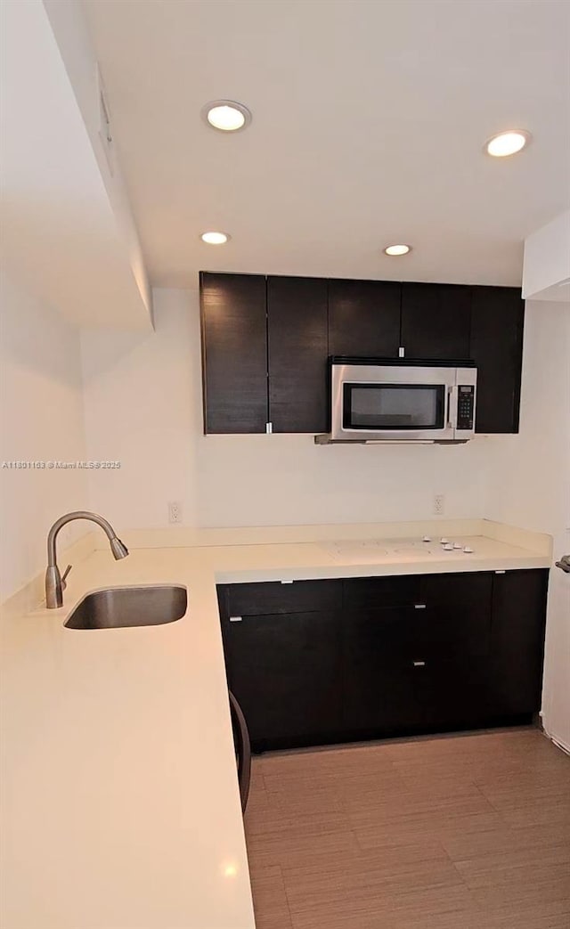 1000 W Ave Unit 715, Miami Beach, FL 33139 - kitchen featuring stainless steel microwave, a sink, light countertops, recessed lighting, and dark cabinetry