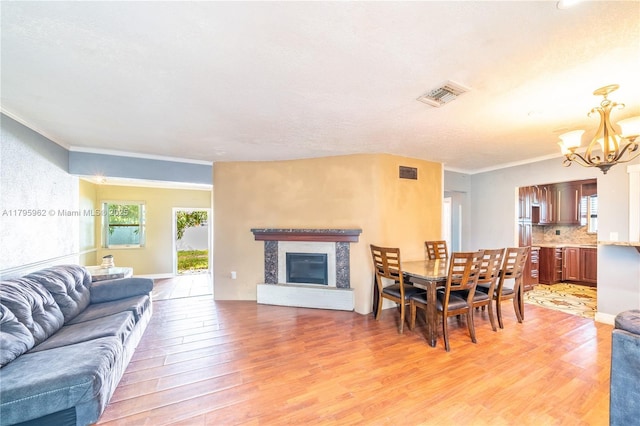 18000 NW 6th Pl, Miami Gardens, FL 33169 - dining space featuring a chandelier, light wood finished floors, crown molding, and a glass covered fireplace