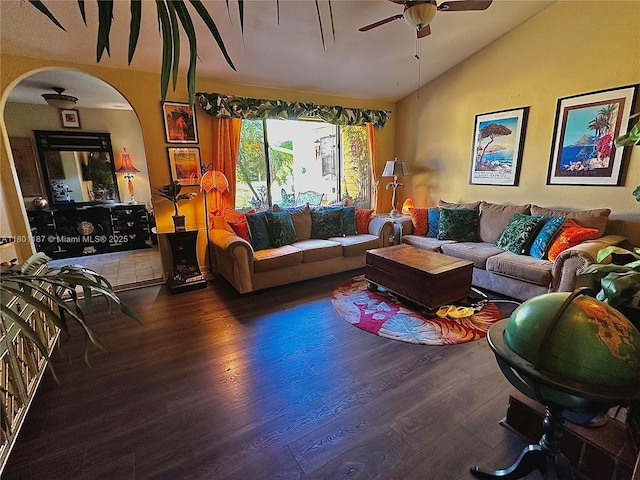 living area featuring lofted ceiling, arched walkways, a ceiling fan, and wood finished floors