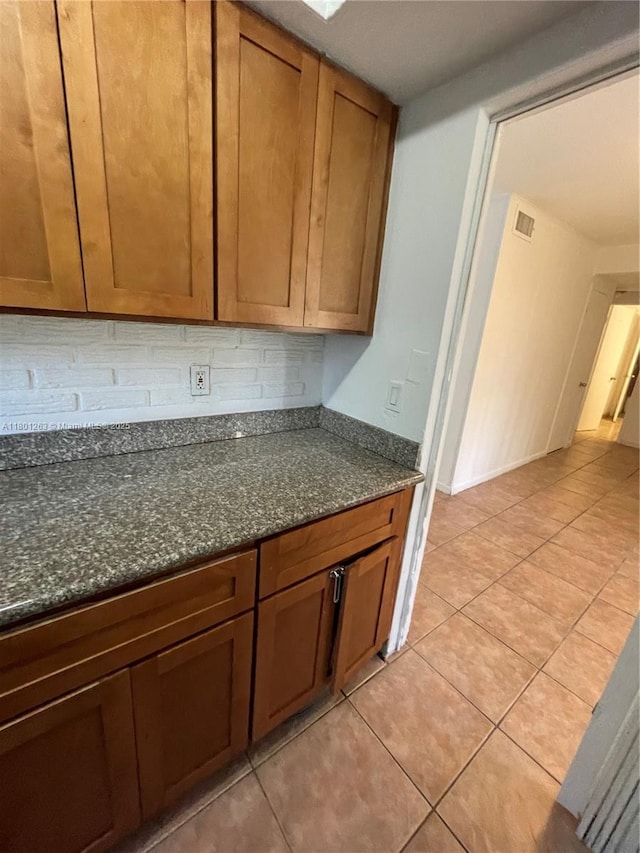 7841 Dunham Blvd Unit 6, Miami, FL 33138 - kitchen with light tile patterned flooring, dark stone counters, brown cabinetry, and tasteful backsplash