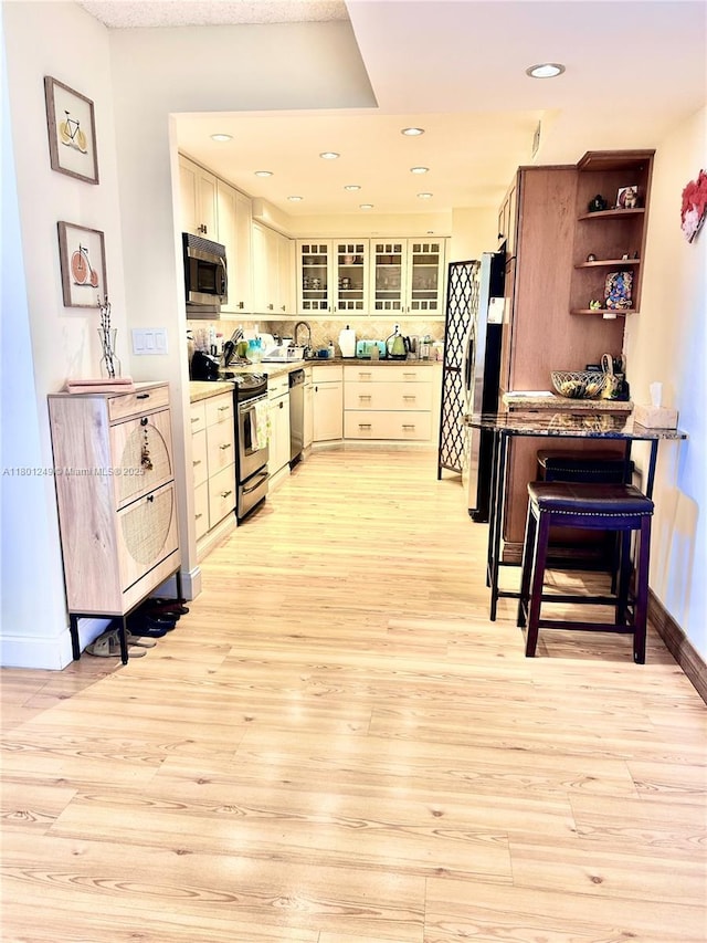 600 Three Islands Blvd Unit 905, Hallandale Beach, FL 33009 - kitchen featuring stainless steel appliances, light wood-style flooring, baseboards, glass insert cabinets, and open shelves