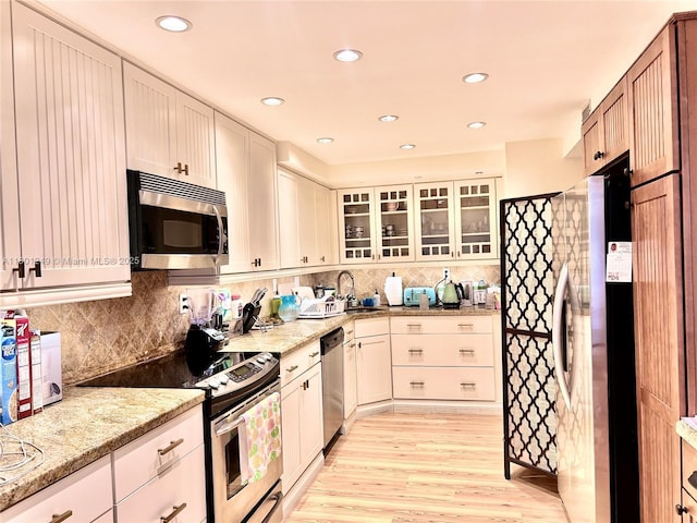 600 Three Islands Blvd Unit 905, Hallandale Beach, FL 33009 - kitchen featuring appliances with stainless steel finishes, a sink, tasteful backsplash, light wood-style flooring, and glass insert cabinets