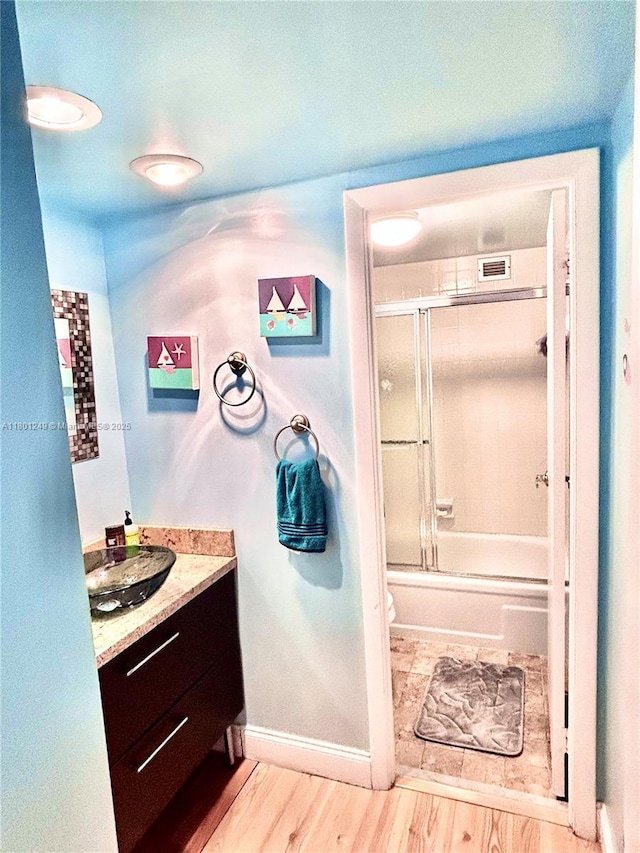 600 Three Islands Blvd Unit 905, Hallandale Beach, FL 33009 - bathroom featuring vanity, wood finished floors, toilet, bath / shower combo with glass door, and baseboards