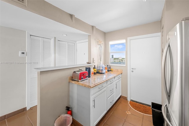 121 Golden Isles Dr Unit 905, Hallandale Beach, FL 33009 - kitchen featuring freestanding refrigerator, white cabinetry, light tile patterned floors, and baseboards