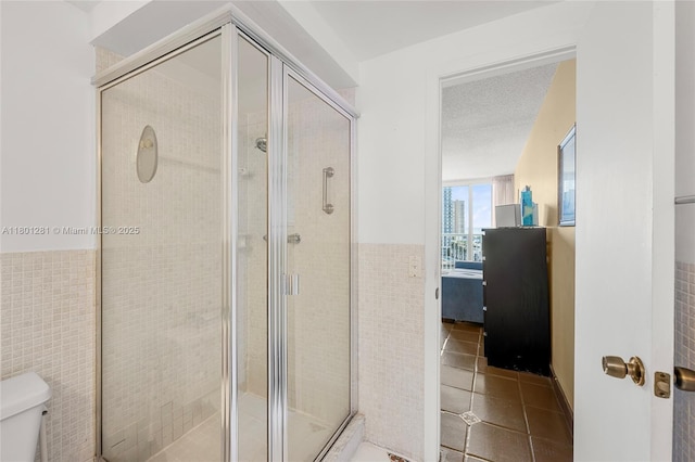 121 Golden Isles Dr Unit 905, Hallandale Beach, FL 33009 - full bath featuring tile walls, toilet, tile patterned flooring, a stall shower, and wainscoting