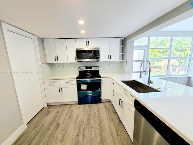 4230 NW 52nd Ave, Lauderdale Lakes, FL 33319 - kitchen featuring stainless steel appliances, a sink, light wood finished floors, open shelves, and light countertops