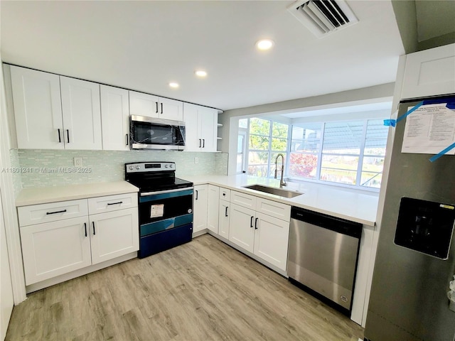 4230 NW 52nd Ave, Lauderdale Lakes, FL 33319 - kitchen featuring appliances with stainless steel finishes, a sink, open shelves, light countertops, and tasteful backsplash