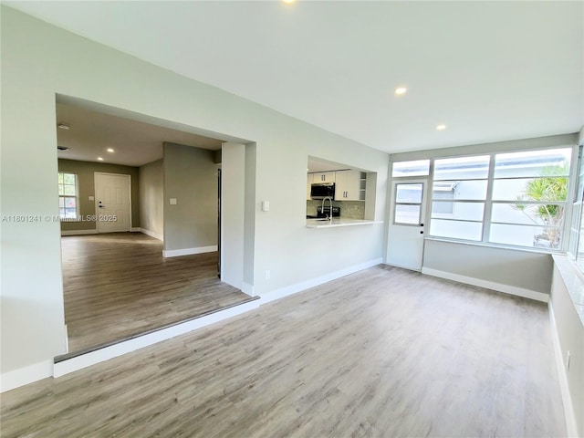 4230 NW 52nd Ave, Lauderdale Lakes, FL 33319 - unfurnished living room featuring wood finished floors, baseboards, recessed lighting, and a sink