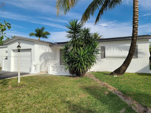 4230 NW 52nd Ave, Lauderdale Lakes, FL 33319 - view of side of home featuring a garage, a lawn, stucco siding, and driveway