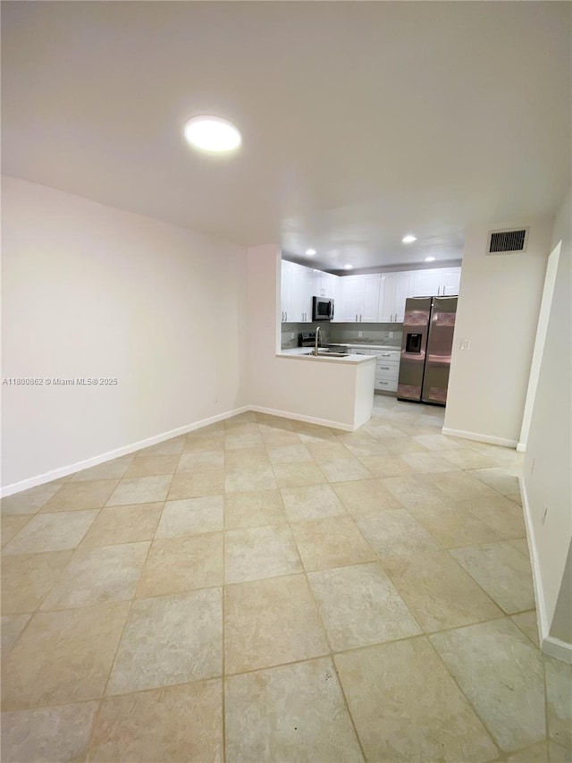 unfurnished living room with baseboards, a sink, recessed lighting, and light tile patterned flooring