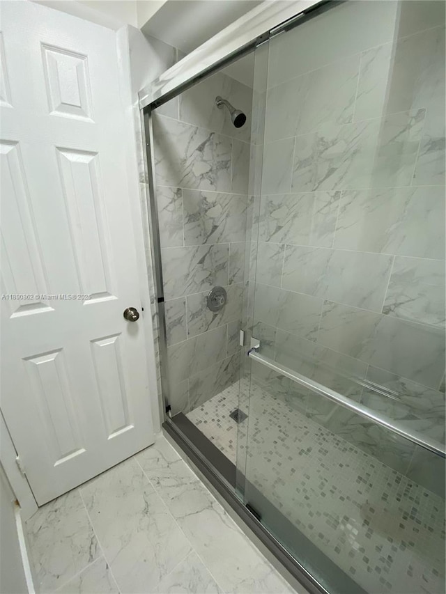 full bathroom with a shower stall and marble look tile flooring