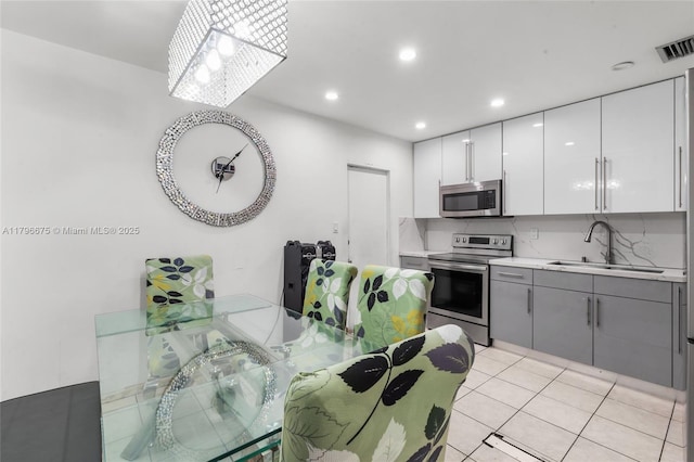 621 E 8th St, Hialeah, FL 33010 - kitchen featuring stainless steel appliances, gray cabinets, light countertops, white cabinets, and light tile patterned flooring
