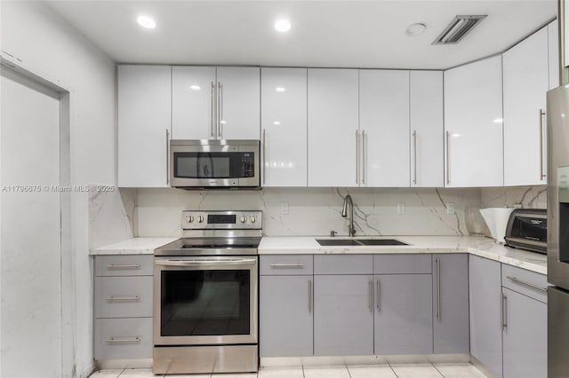621 E 8th St, Hialeah, FL 33010 - kitchen featuring appliances with stainless steel finishes, gray cabinetry, and white cabinets