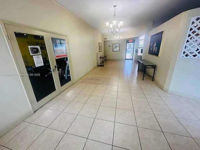 hall featuring a chandelier, light tile patterned flooring, lofted ceiling, and baseboards