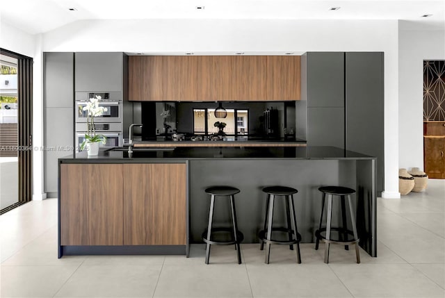 4275 Prairie Ave, Miami Beach, FL 33140 - kitchen with dark countertops, double oven, a sink, a kitchen bar, and vaulted ceiling
