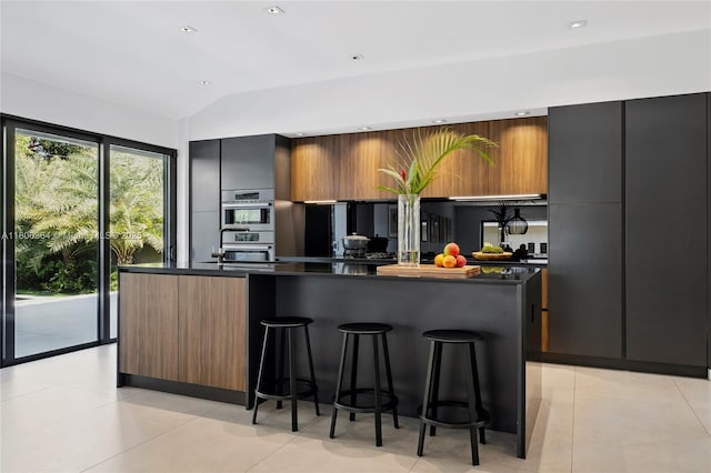 4275 Prairie Ave, Miami Beach, FL 33140 - kitchen with modern cabinets, dark countertops, a kitchen bar, vaulted ceiling, and a spacious island