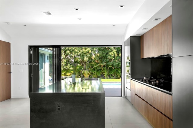 4275 Prairie Ave, Miami Beach, FL 33140 - kitchen featuring modern cabinets, dark countertops, black cooktop, and light tile patterned flooring
