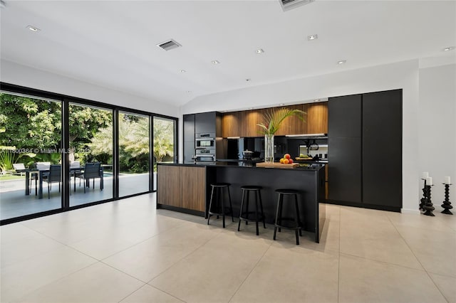 4275 Prairie Ave, Miami Beach, FL 33140 - kitchen featuring dark countertops, modern cabinets, light tile patterned floors, a kitchen island, and vaulted ceiling