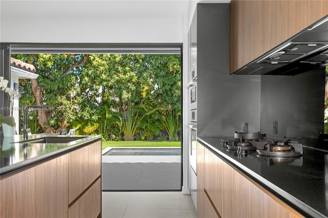 4275 Prairie Ave, Miami Beach, FL 33140 - kitchen featuring under cabinet range hood, modern cabinets, a sink, and stainless steel oven