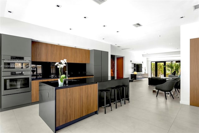 4275 Prairie Ave, Miami Beach, FL 33140 - kitchen with dark countertops, double oven, a breakfast bar area, and modern cabinets