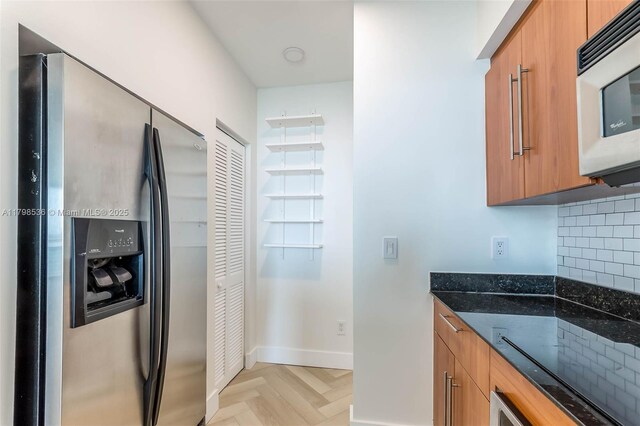 335 S Biscayne Blvd Unit 1012, Miami, FL 33131 - kitchen with stainless steel appliances, dark stone countertops, brown cabinets, and backsplash