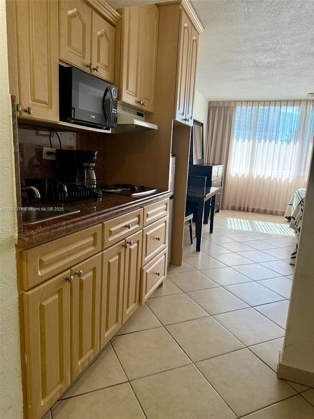 19201 Collins Ave Unit 241, Sunny Isles Beach, FL 33160 - kitchen featuring black microwave, a textured ceiling, under cabinet range hood, light brown cabinetry, and light tile patterned floors
