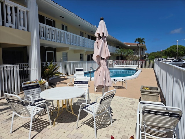 community pool with a patio and fence