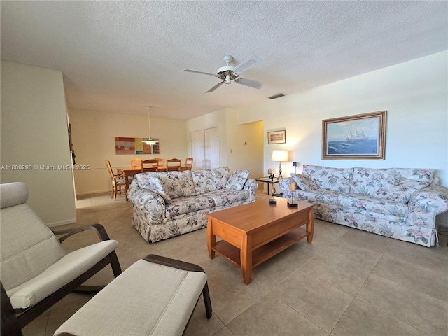 living room featuring ceiling fan and a textured ceiling