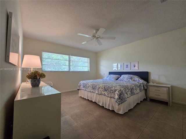 bedroom featuring baseboards, dark tile patterned floors, a textured ceiling, and ceiling fan
