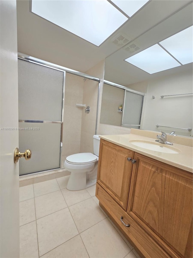 bathroom with a skylight, tile patterned floors, toilet, and a shower with shower door