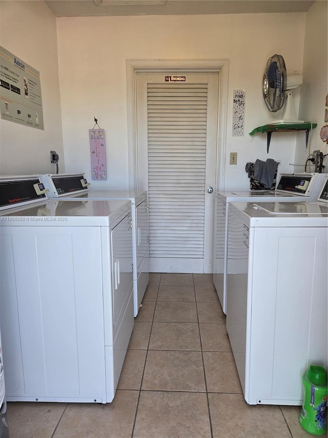 community laundry room with washer and clothes dryer and light tile patterned floors