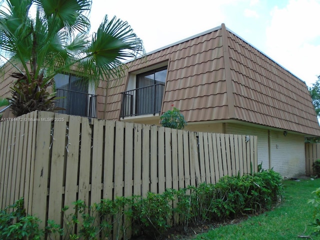 597 Green Springs Pl, West Palm Beach, FL 33409 - view of side of property with mansard roof, a tiled roof, brick siding, and fence