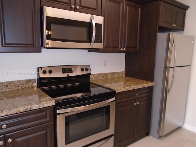 597 Green Springs Pl, West Palm Beach, FL 33409 - kitchen with stainless steel appliances, dark brown cabinets, light tile patterned flooring, and light stone counters