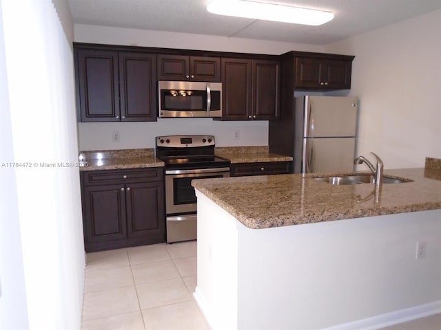 597 Green Springs Pl, West Palm Beach, FL 33409 - kitchen featuring appliances with stainless steel finishes, a sink, dark brown cabinets, light stone countertops, and light tile patterned floors