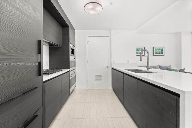 kitchen with a sink, stainless steel gas cooktop, modern cabinets, and a peninsula
