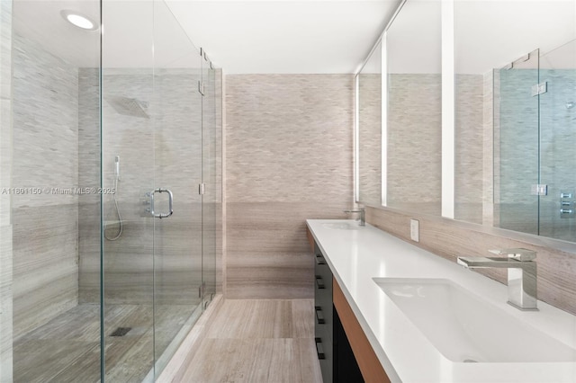 bathroom featuring a shower stall, tile walls, and double vanity