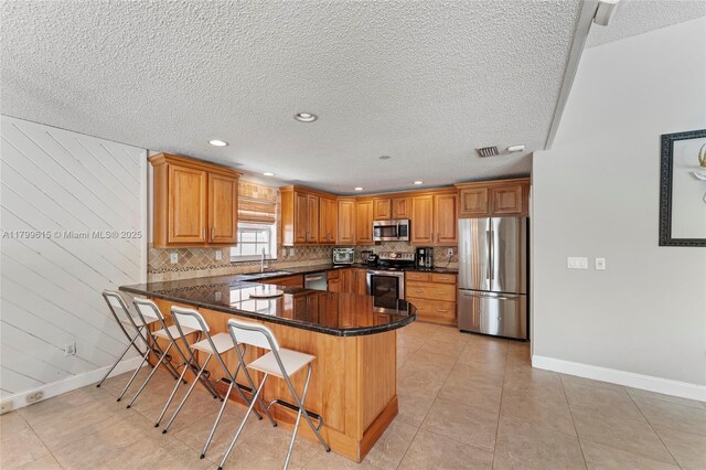 2421 NW 102nd Way, Pembroke Pines, FL 33026 - kitchen with stainless steel appliances, a sink, a peninsula, baseboards, and a textured ceiling