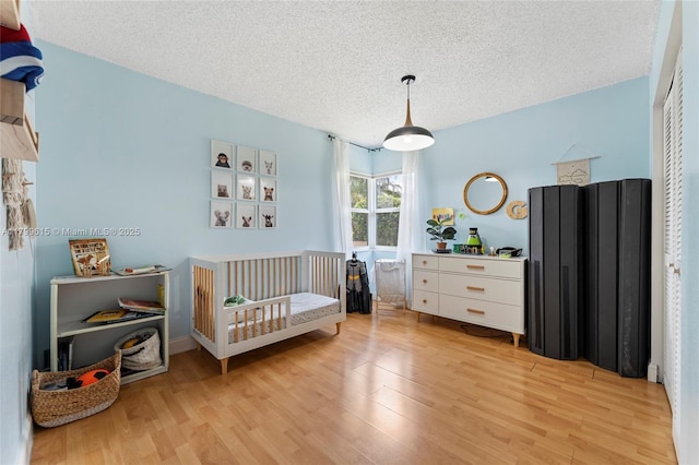 2421 NW 102nd Way, Pembroke Pines, FL 33026 - bedroom featuring light wood-style floors, a textured ceiling, a closet, and a crib