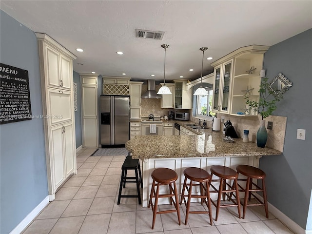 9720 SW 104th Ct, Miami, FL 33176 - kitchen with appliances with stainless steel finishes, wall chimney range hood, cream cabinets, a peninsula, and backsplash