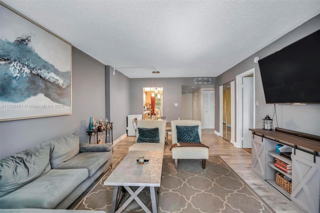 living area featuring light wood-style floors, a textured ceiling, and a chandelier