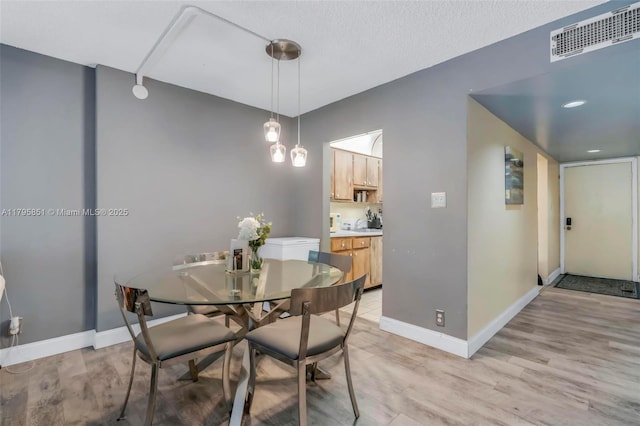 dining area with light wood-style flooring and baseboards